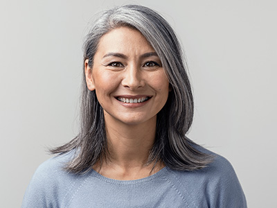 A smiling woman with short hair, wearing a light blue top, against a neutral background.