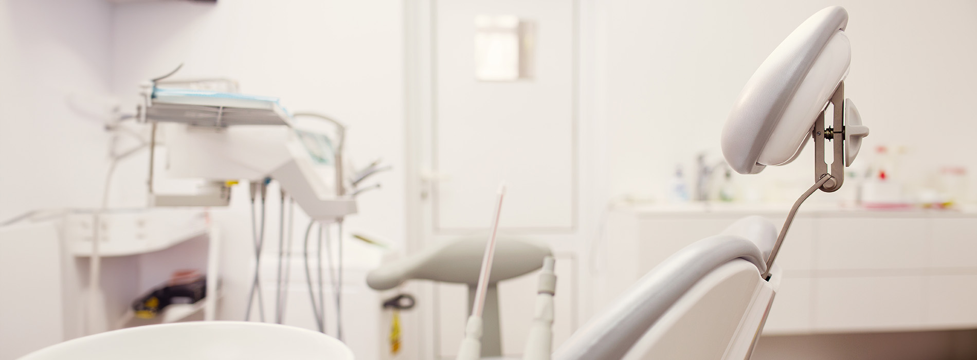 The image shows a modern dental clinic interior with various pieces of equipment, including a dental chair and an X-ray machine.