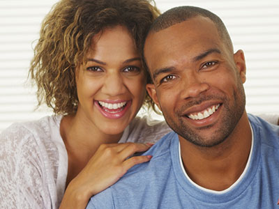 A man and a woman are smiling at the camera, posing for a portrait.